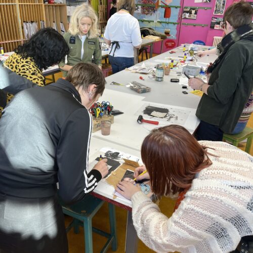 Group of people stood round a table sewing with different types of fabric