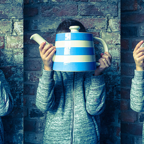 A triptych photo of a young person wearing a grey marl cardigan holding three different pots in front of their face. In the first photo, they are holding a large circular cabbage-style pot in yellow and green. In the second photo they are holding a large Cornish blue and white striped teapot, and in the third photo, they are holding a large two handled pot with a decorative pattern including a cherub in white, blue and green