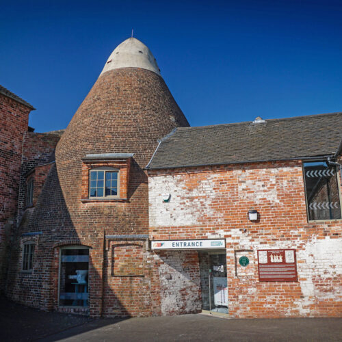 Entrance to Sharpe's Pottery Museum in a red brick industrial building attached to a large circular bottle bank with a white top