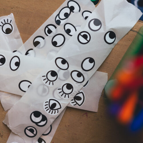 Strips of stickers of eyes, some with eyelashes, some half closed in black and white on a wooden table